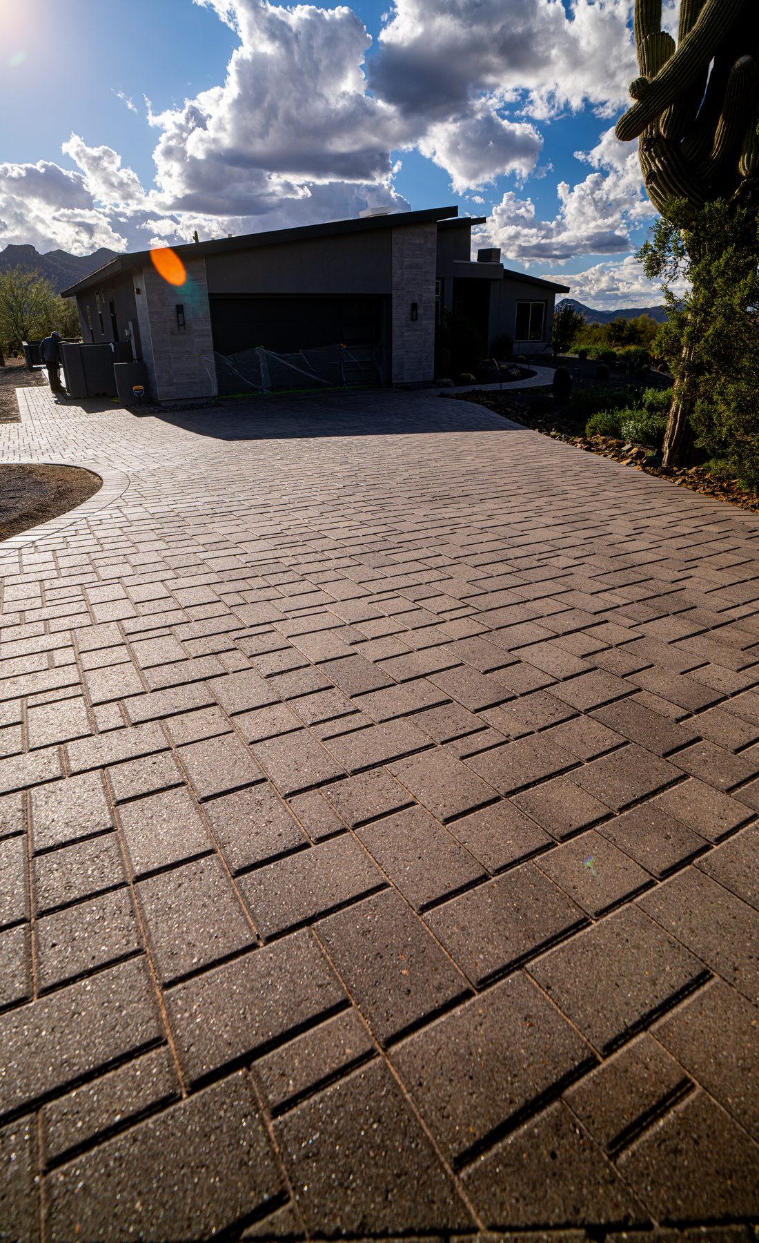 Modern home with sealed paver driveway, dramatic clouds